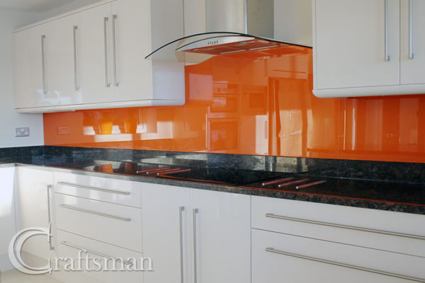 White units, black granite worktops, orange glass splashbacks